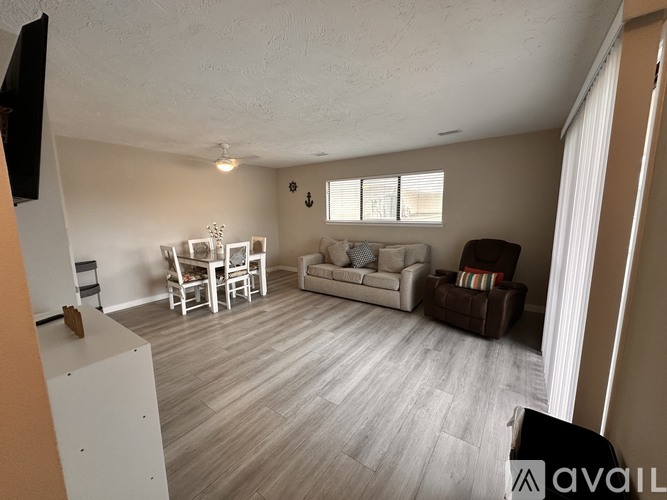 A living room with a white sofa, a white chair, and a brown armchair.