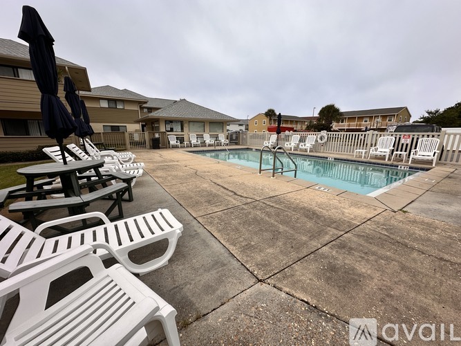 A pool area with sun loungers and umbrellas.