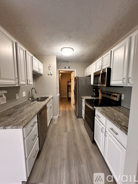 A kitchen with white cabinets and a wooden floor.