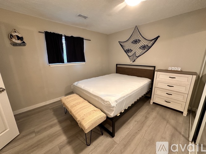 A bedroom with a bed, a bench, and a wall hanging.