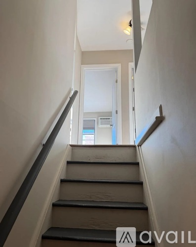 A staircase with a black railing leading to a doorway.