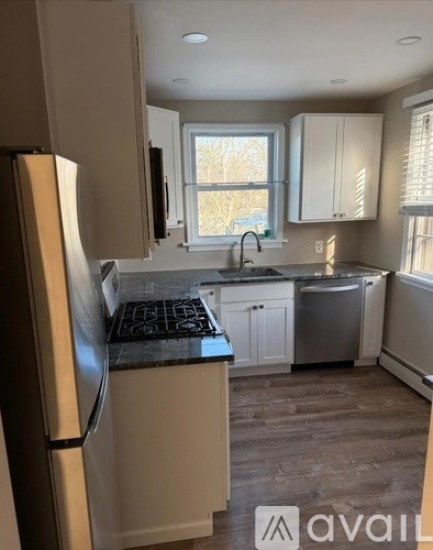 A kitchen with a refrigerator, cabinets, and a window.