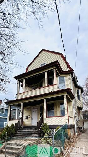A two-story house with a front porch and a fence.