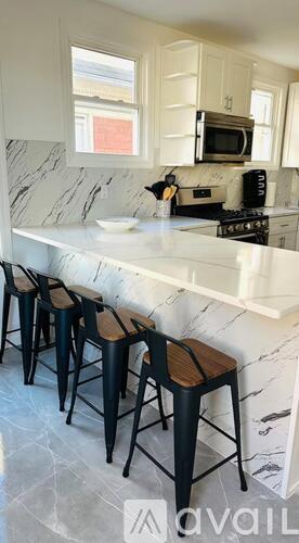 A kitchen with a marble countertop and bar stools.
