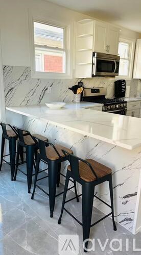 A kitchen with a marble countertop and bar stools.