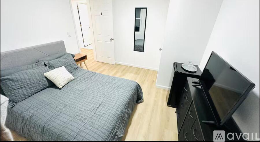 A bedroom with a bed, a dresser, and a television.