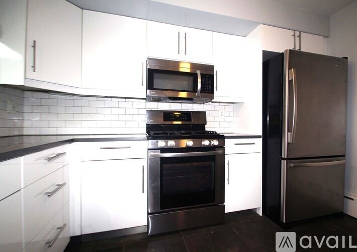 A kitchen with white cabinets and a black refrigerator.