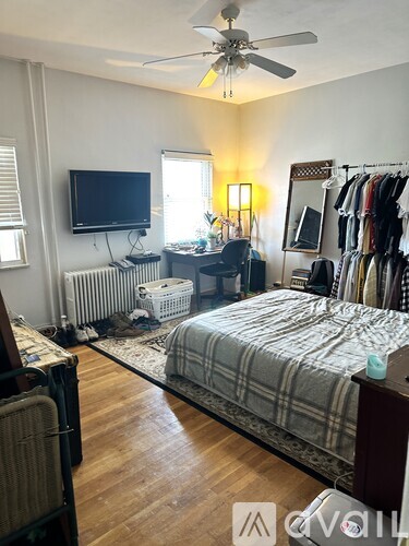 A bedroom with a bed, a television, a desk, and a closet.