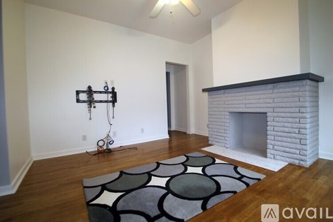 A living room with a fireplace and a rug on the floor.