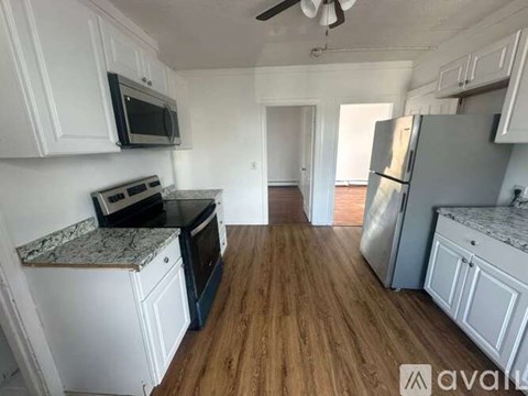 A kitchen with white cabinets and a wooden floor.