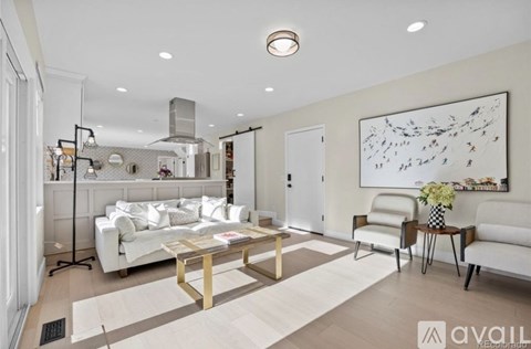 A modern living room with a white sofa, a wooden coffee table, and a large abstract painting on the wall.