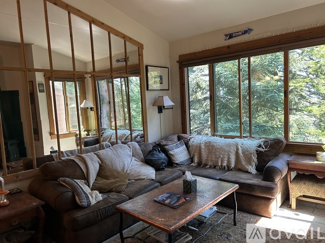 A living room with a couch, a coffee table, and a large window.