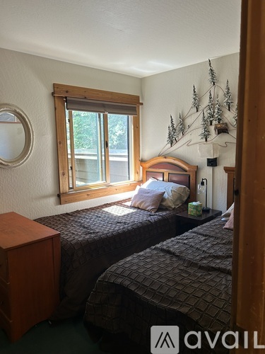 A bedroom with two beds and a wooden nightstand.