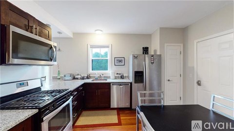 A kitchen with a black counter top and stainless steel appliances.