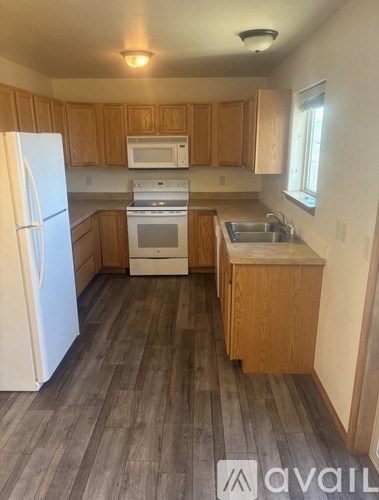 A kitchen with a white fridge, white microwave, white oven, and wooden cabinets.