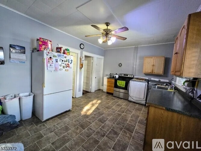 A kitchen with tile flooring and a refrigerator filled with magnets.