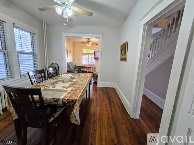 A dining room with a table set for two and a ceiling fan.