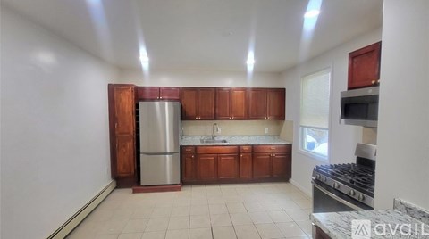 A kitchen with wooden cabinets and a stainless steel refrigerator.