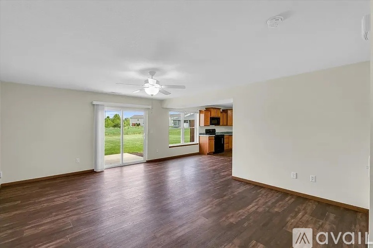A spacious room with wooden floors and a ceiling fan.