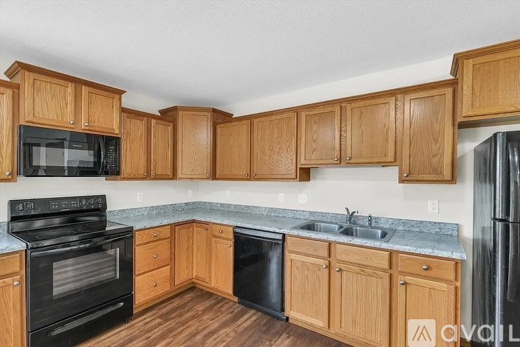 A kitchen with wooden cabinets and a black refrigerator.