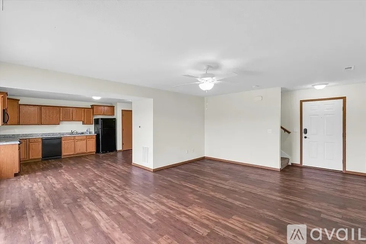 A spacious room with wooden flooring and a kitchen area to the left.