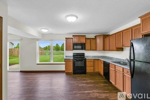 A kitchen with wooden cabinets and a black refrigerator.