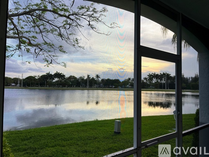 A view of a lake through a window with a tree branch in the foreground.