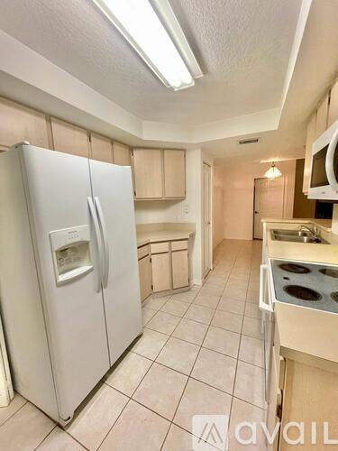 A kitchen with a white fridge and tiled floor.
