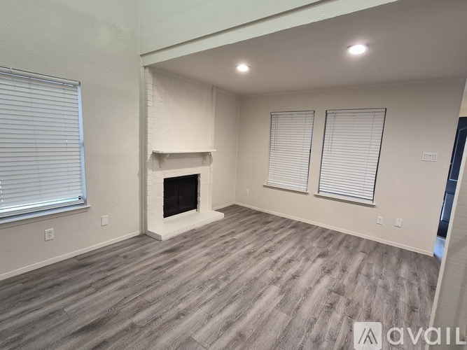 A spacious living room with a fireplace and wood flooring.