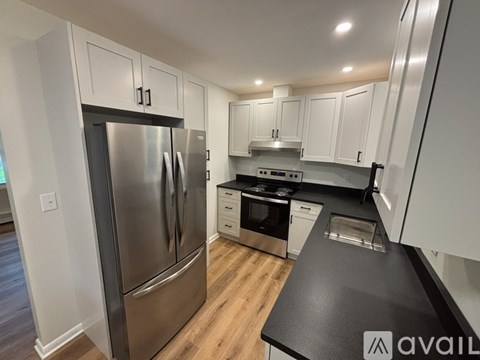 A modern kitchen with a stainless steel refrigerator and black countertops.