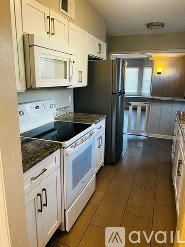 A kitchen with white cabinets and a granite countertop.