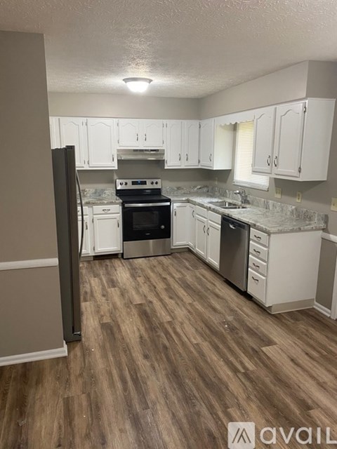 A kitchen with white cabinets and a wooden floor.