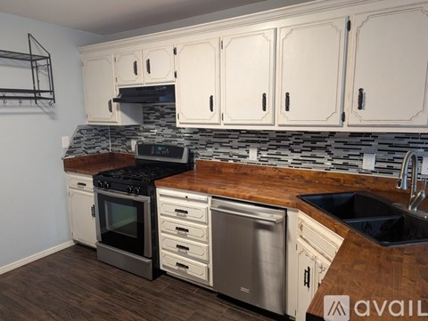 A kitchen with white cabinets and a wooden countertop.