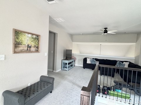 A living room with a grey sofa and a painting on the wall.