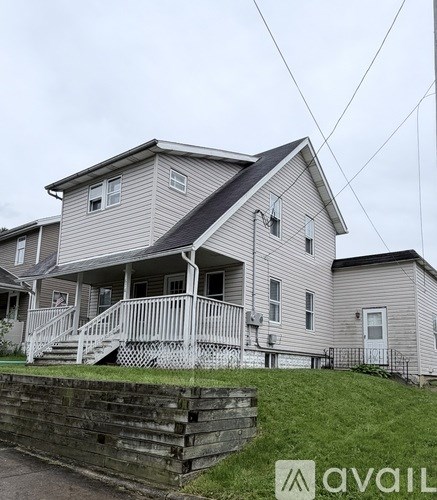 A two-story house with a grey exterior and a white porch.
