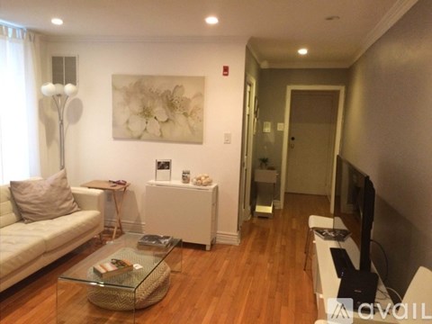 A living room with a white sofa, a glass coffee table, and a painting on the wall.