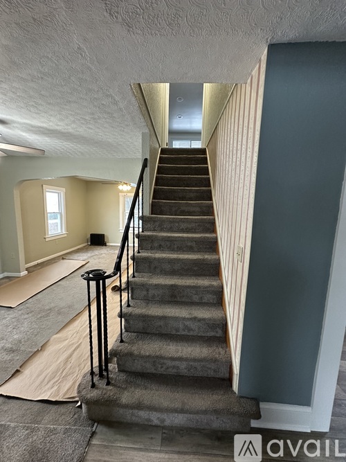 A staircase with a carpeted landing and a black handrail.