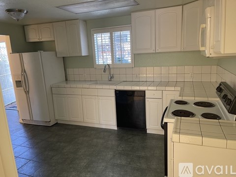 A kitchen with white cabinets and a black dishwasher.