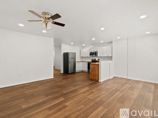 A spacious room with wooden flooring and a ceiling fan.