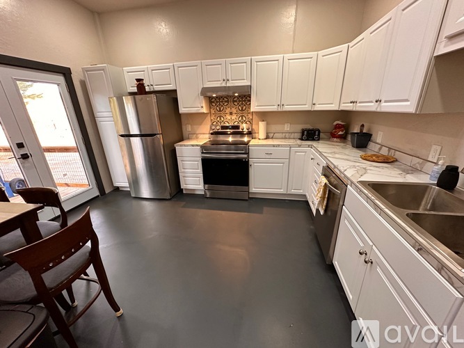 A kitchen with white cabinets and a stainless steel refrigerator.