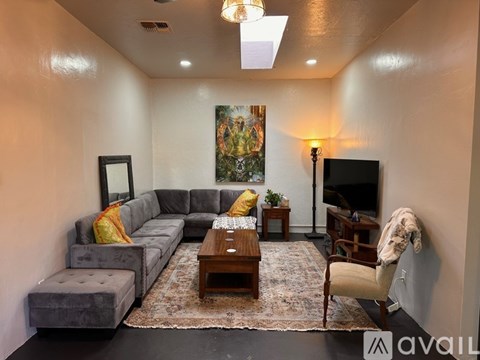 A living room with a grey couch, a coffee table, and a painting on the wall.