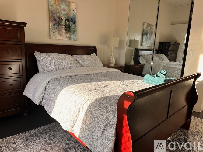 A bedroom with a large bed and a painting on the wall.