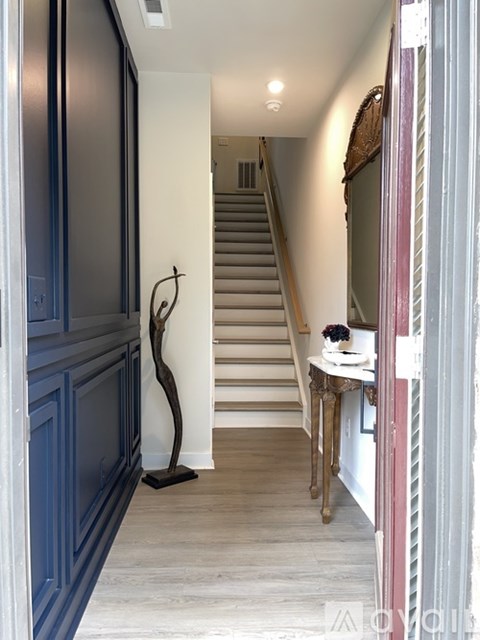 A hallway with a staircase and a table with a vase of flowers on it.