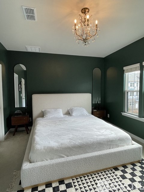 A bedroom with a white bed and a chandelier.