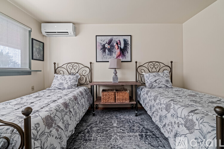 A bedroom with two beds and a nightstand in between.