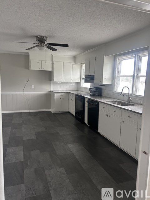 A kitchen with white cabinets and a black dishwasher.