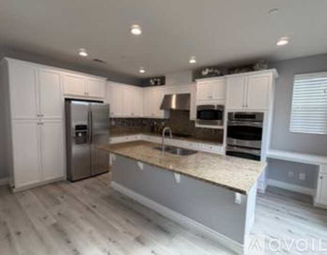 A kitchen with a refrigerator, microwave, oven, and sink.