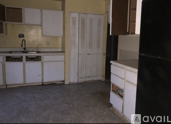 A kitchen with white cabinets and a black counter.