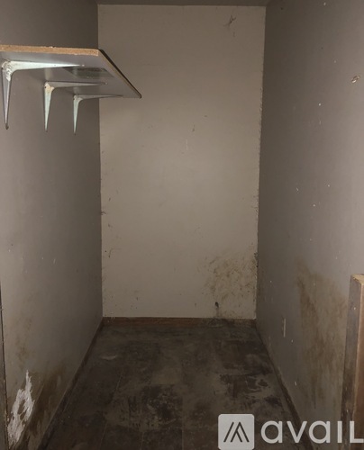 A dirty hallway with a metal shelf on the wall.