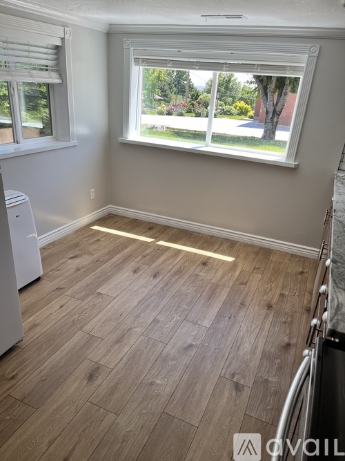 A kitchen with a white dishwasher and wooden flooring.
